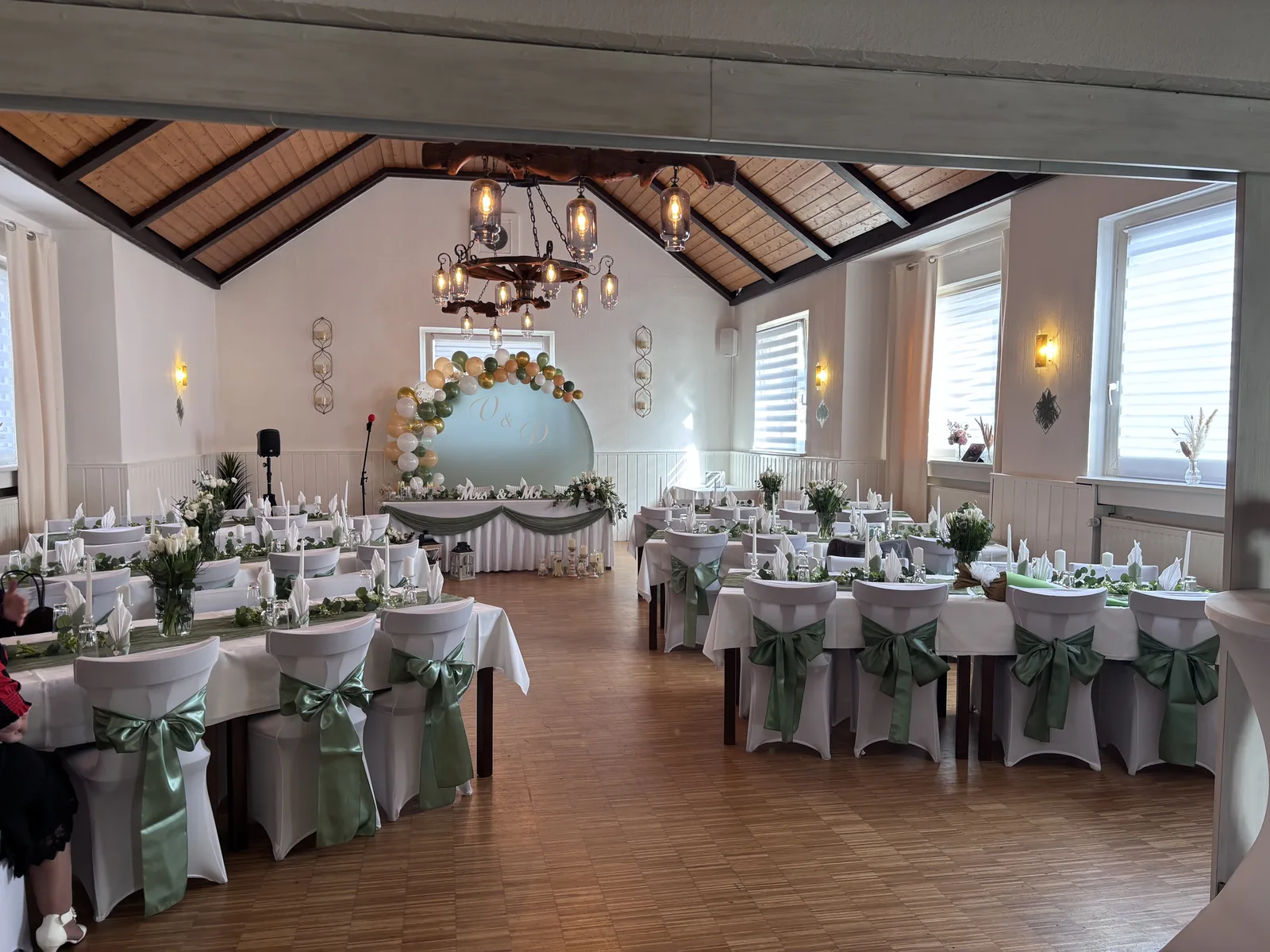 Eingedeckte Tafeln mit Hussen und Blumenschmuck im Festsaal des Restaurants Mamuschka